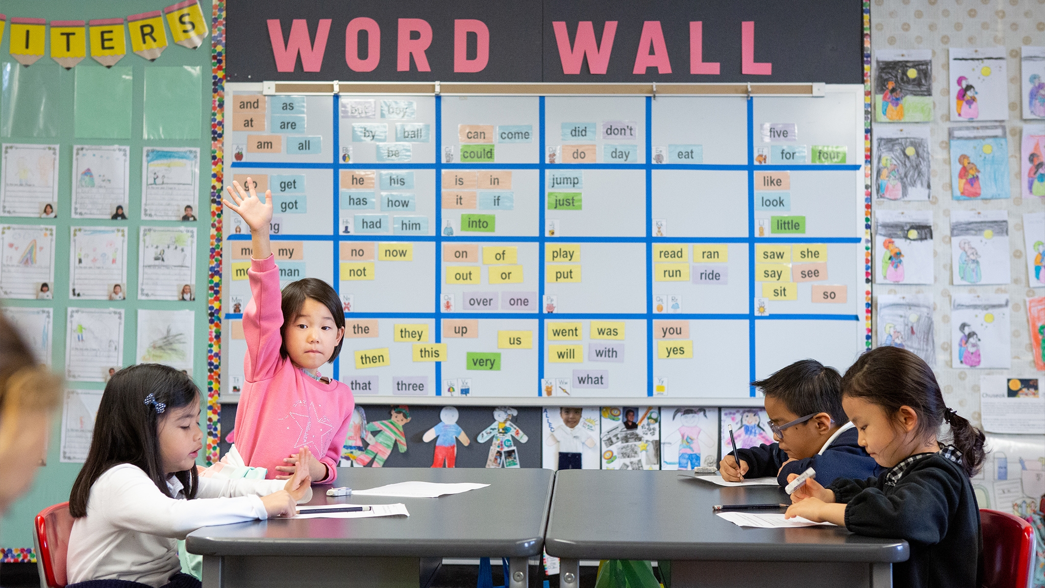 A kindergarten student raises her hand in a dual-language immersion class.