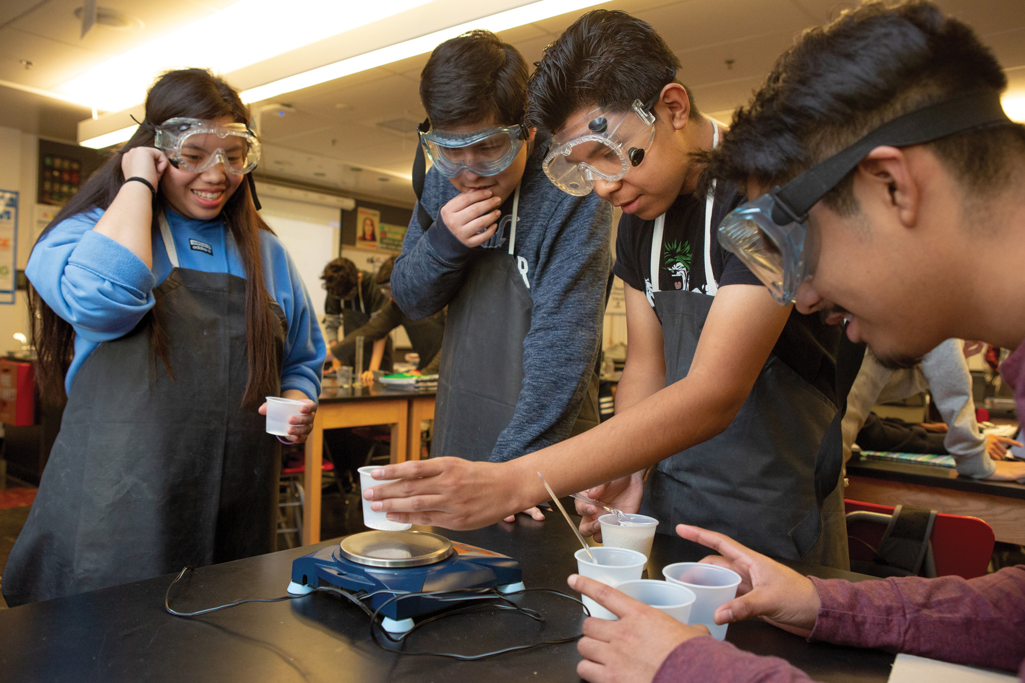 Three high school boys and one high school girl work together on an experiment in chemistry class.