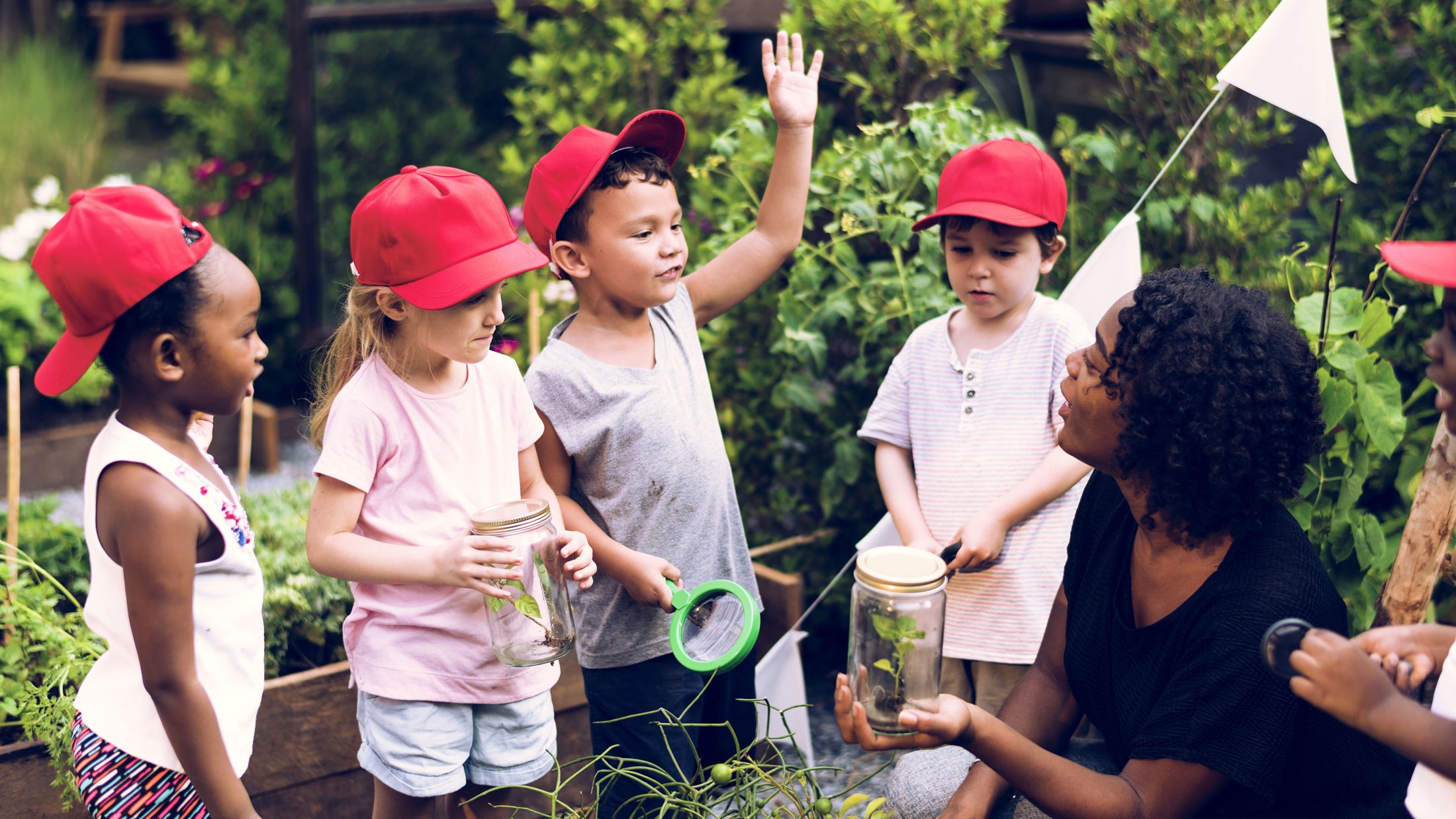 Teacher instructing children outside in a garden